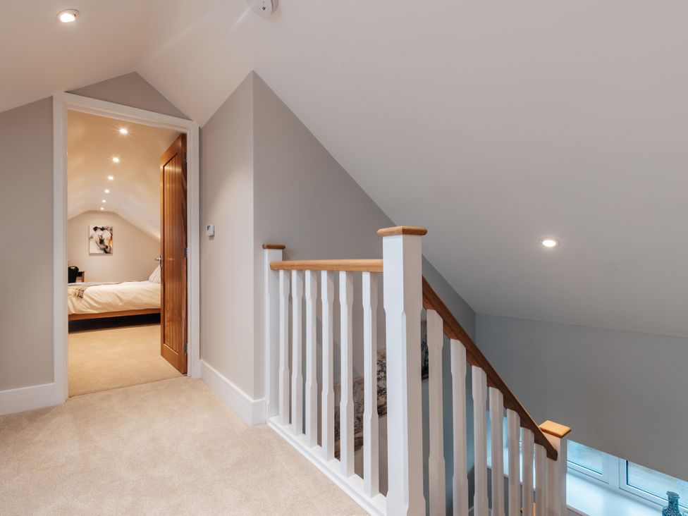 A landing with a staircase and door to a bedroom at The Stables in Catworth