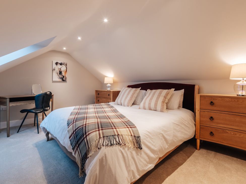 A bedroom with a bed, desk, and artwork at The Stables in Catworth