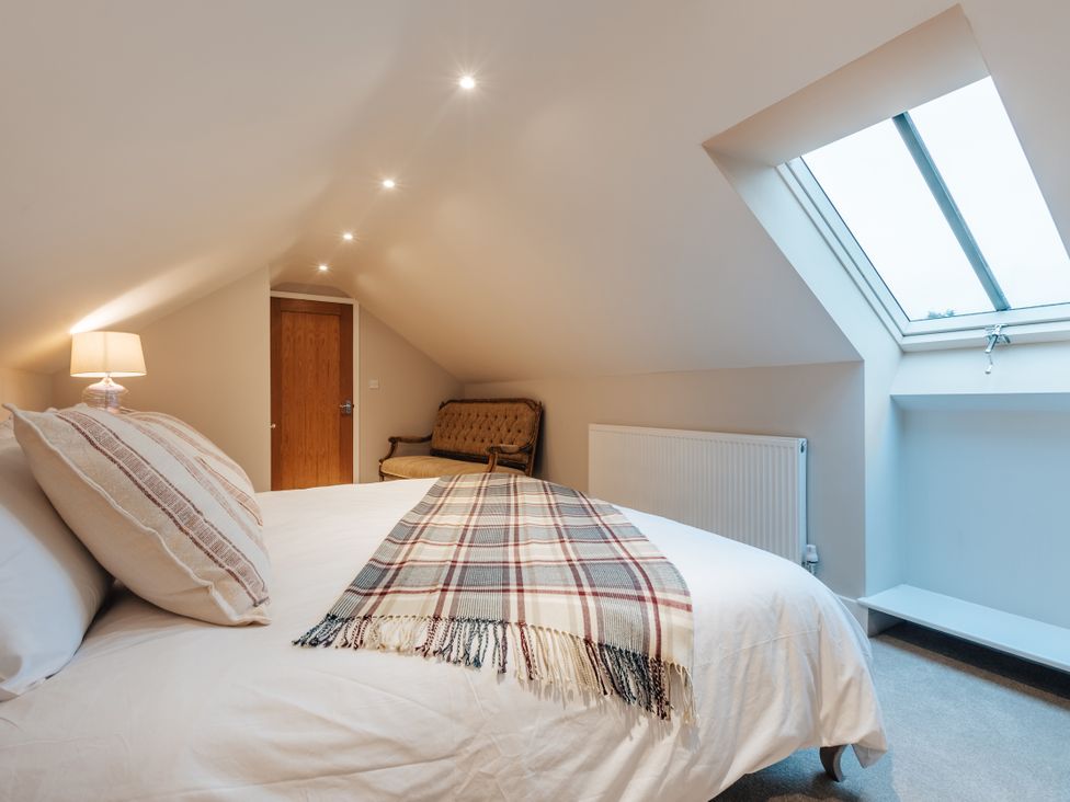 A bedroom with a bed and a lamp at The Stables in Catworth