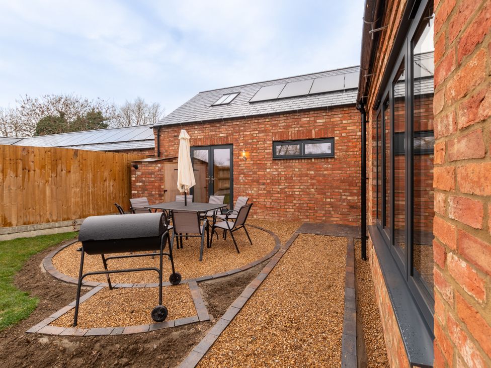 A garden with a table and chairs and barbecue at The Stables in Catworth