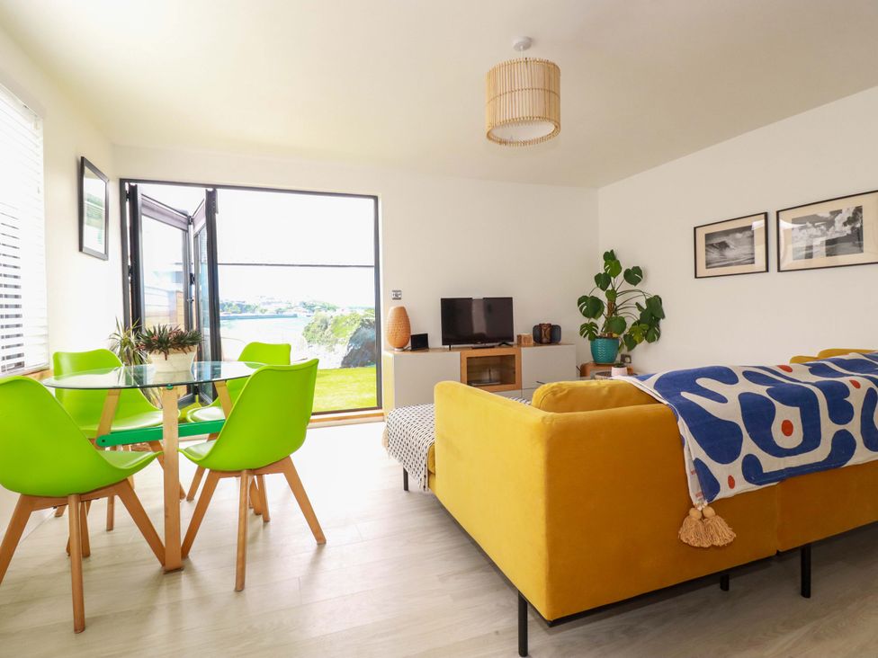 A living room with a sofa and dining area at La Casita in Newquay