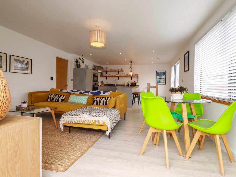 A living room with a yellow sofa and a dining table at La Casita in Newquay