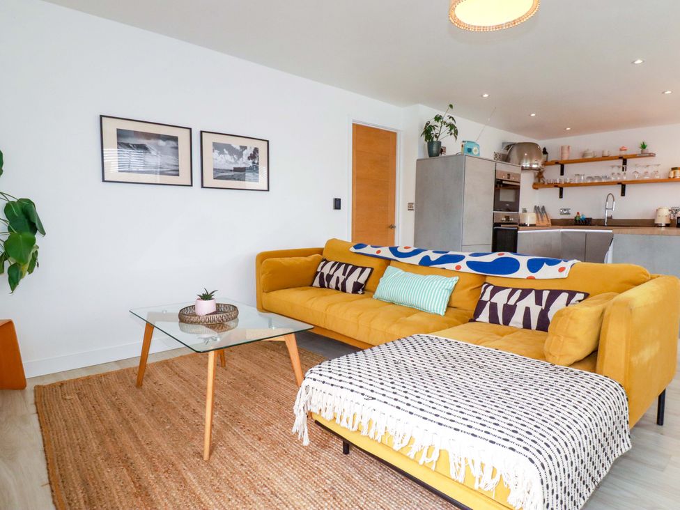 A living room with a yellow sofa and coffee table at La Casita in Newquay