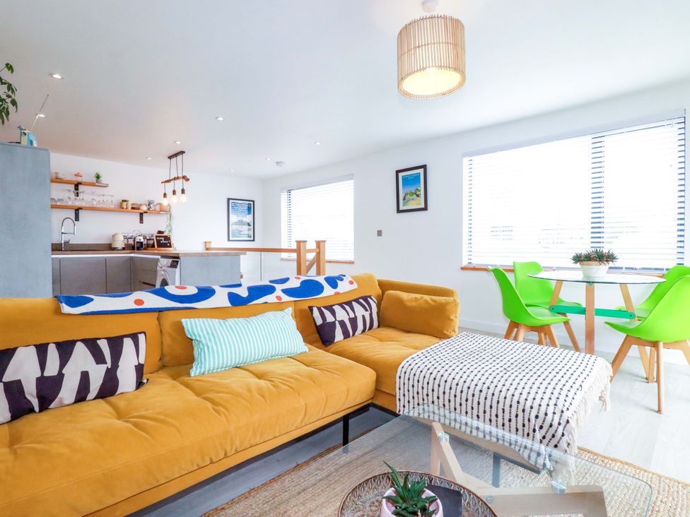 A living room with a sofa and dining area at La Casita in Newquay