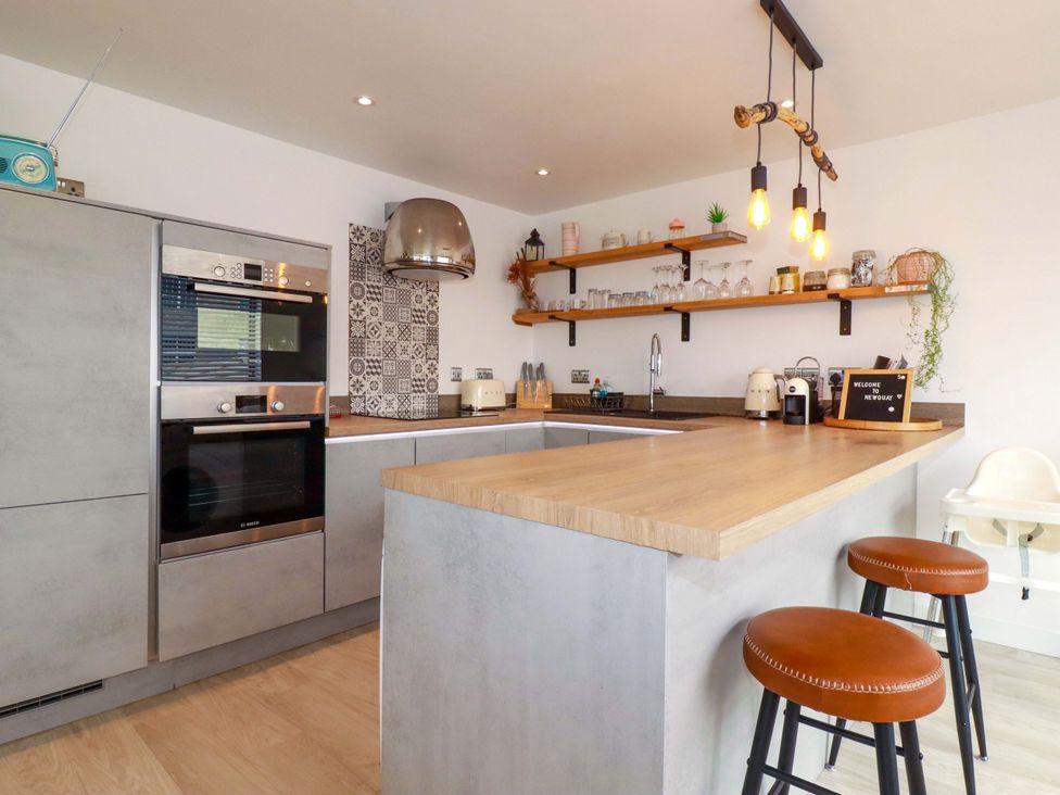 A kitchen with modern appliances and bar stools at La Casita in Newquay