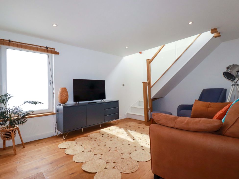 A living room with a television and a staircase at La Casita in Newquay