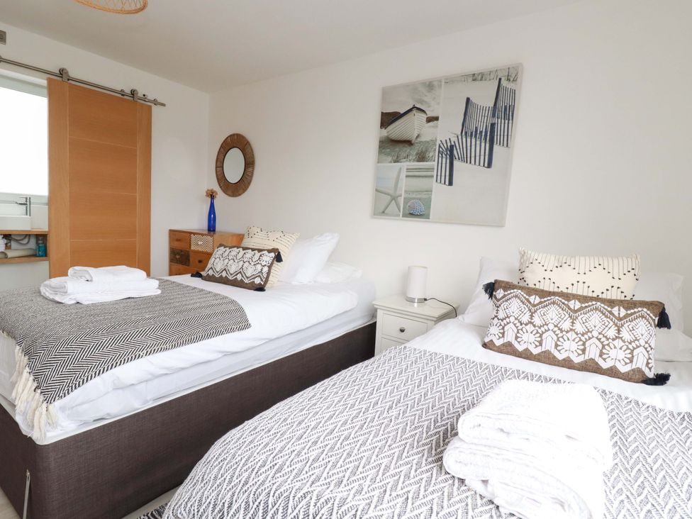 A bedroom with two beds and a side table at La Casita in Newquay