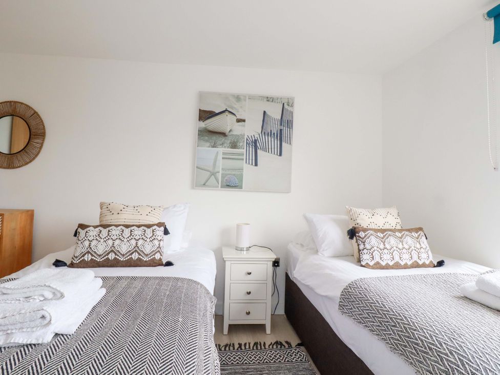 A bedroom with two beds and decorative pillows at La Casita in Newquay