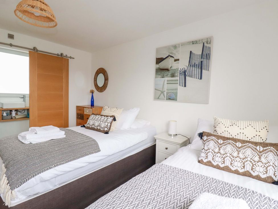 A bedroom with two beds and a mirror at La Casita in Newquay