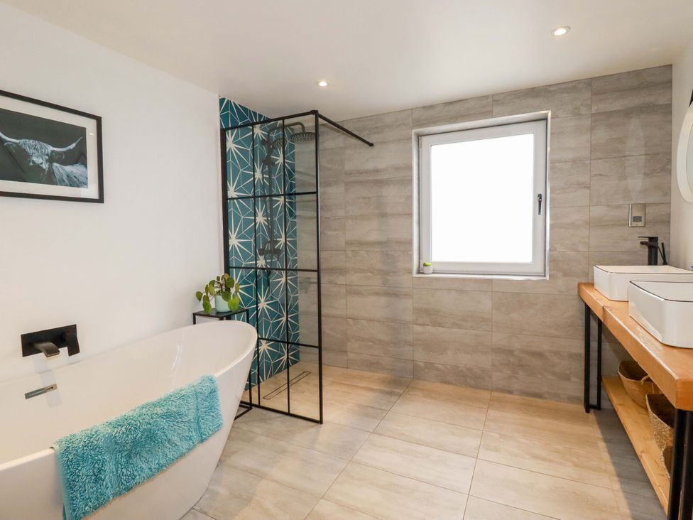 A bathroom with a bathtub, shower, and sink at La Casita in Newquay