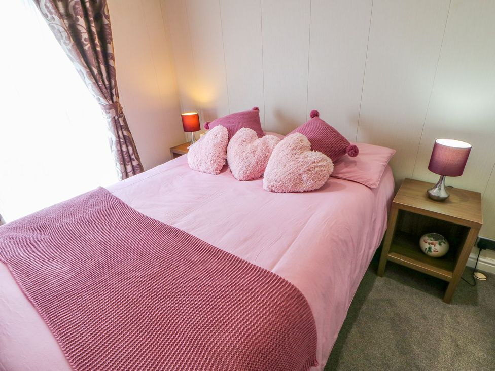 A bedroom with a pink bed and decorative pillows at 37 Horizon Park in Hartlepool
