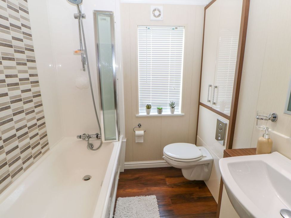 A bathroom with a bathtub, shower, toilet, and sink at 37 Horizon Park in Hartlepool