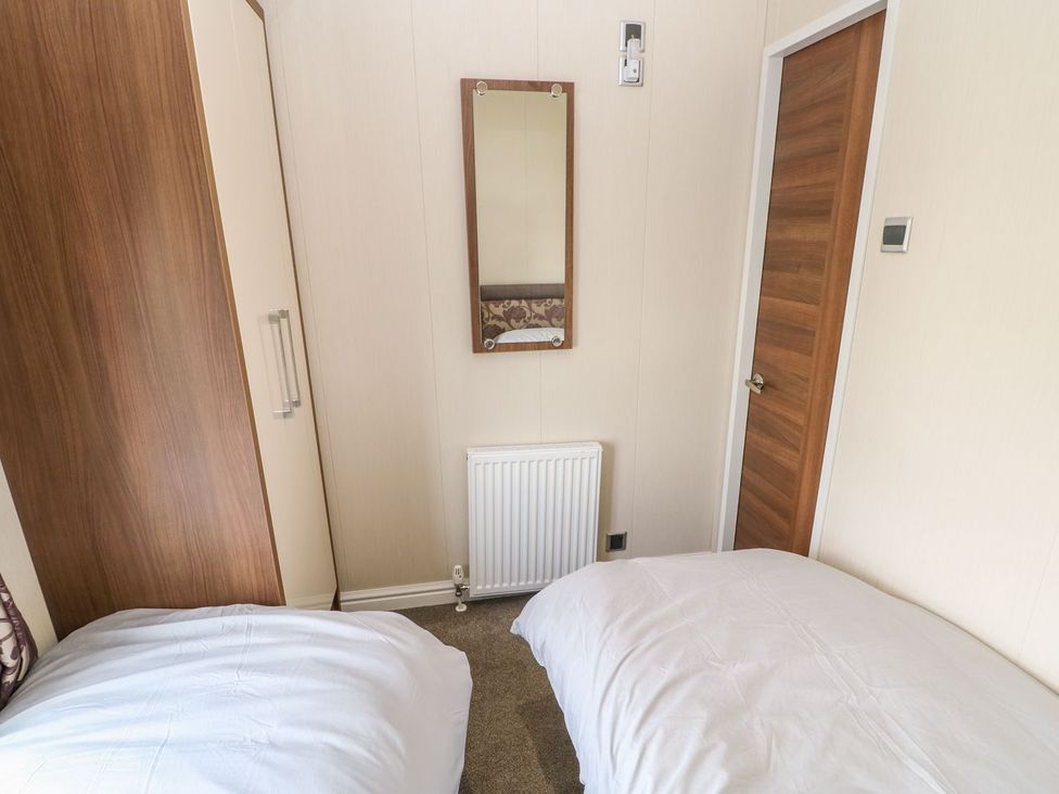 A bedroom with two beds and a wardrobe at 37 Horizon Park in Hartlepool