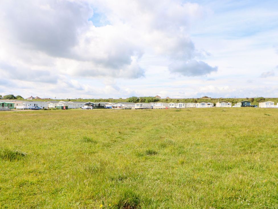 An open field with caravans in the background at 37 Horizon Park in Hartlepool