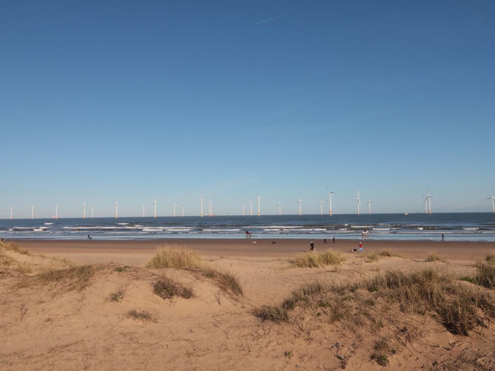 A beach with people walking near the ocean at Caravan 132 Redcar