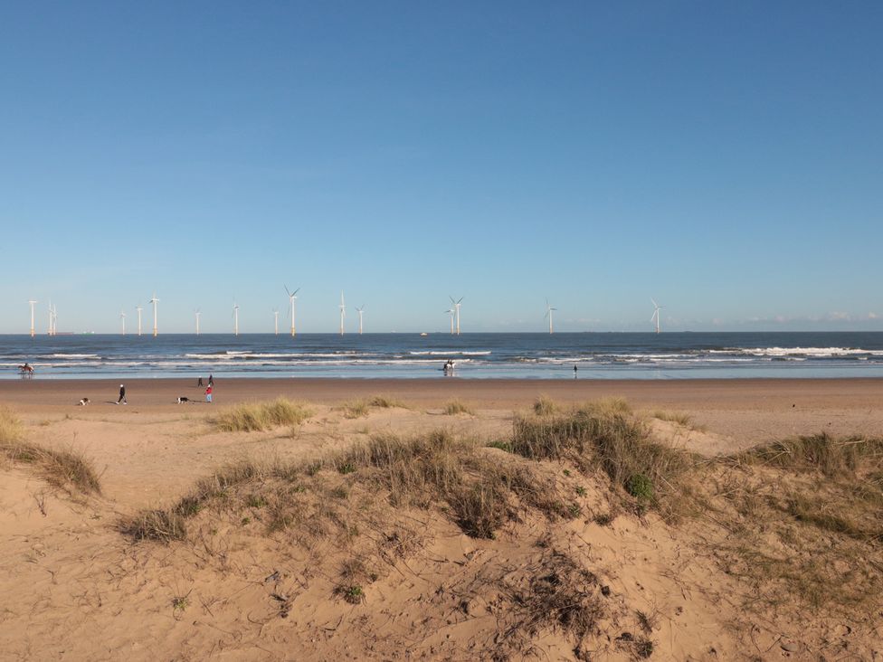 A beach with sand dunes and wind turbines at Caravan 132 in Redcar