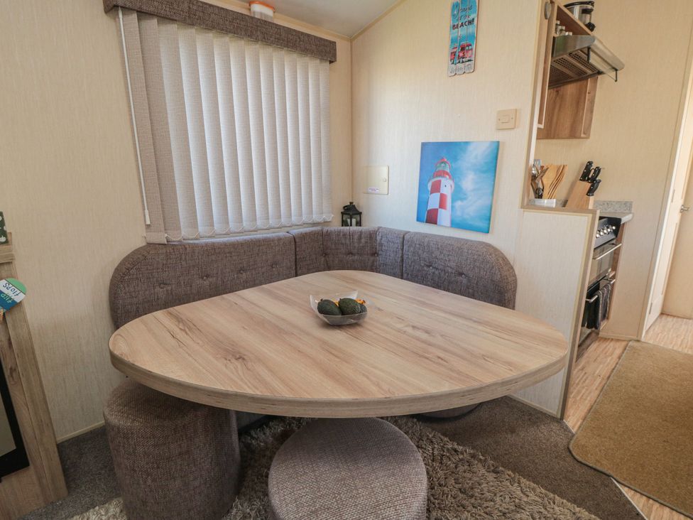 A dining area with a round table and seating at Caravan 132 in Redcar