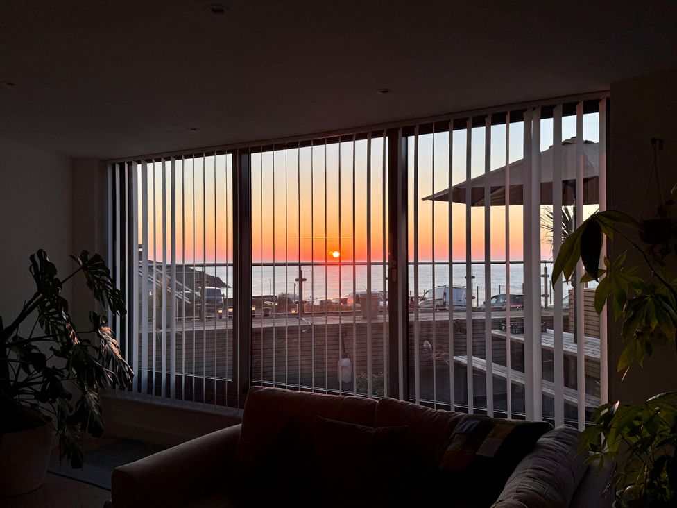 A living room with a view of the sunset over the ocean at Apartment 29 Newquay