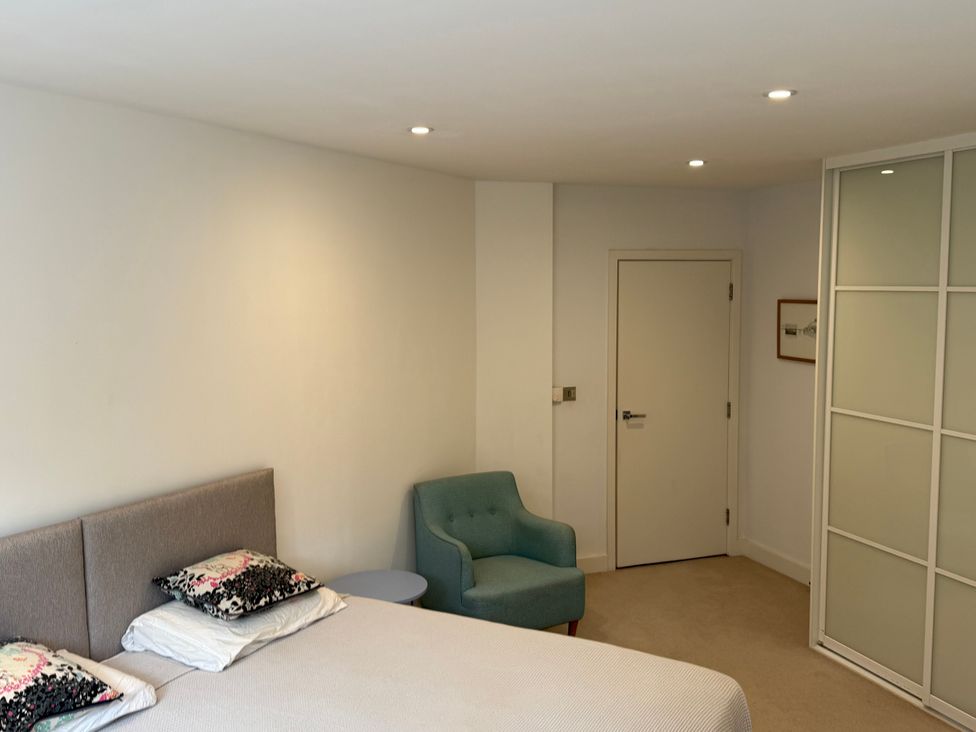 A bedroom with a bed, chair, and wardrobe at Apartment 29 in Newquay