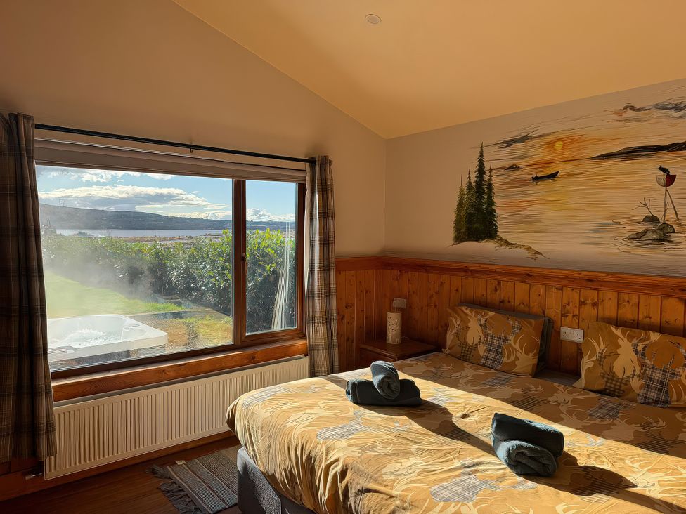 A bedroom with a bed and window overlooking a landscape at No 4 in Enniskillen