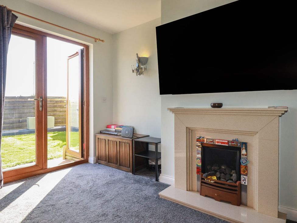 A living room with a fireplace and television at Carnweather in Newquay