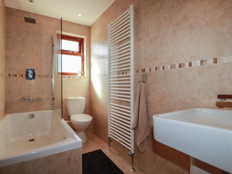 A bathroom with a bathtub, toilet, and wash basin at Carnweather in Newquay