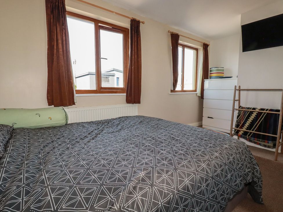 A bedroom with a bed and windows at Carnweather in Newquay