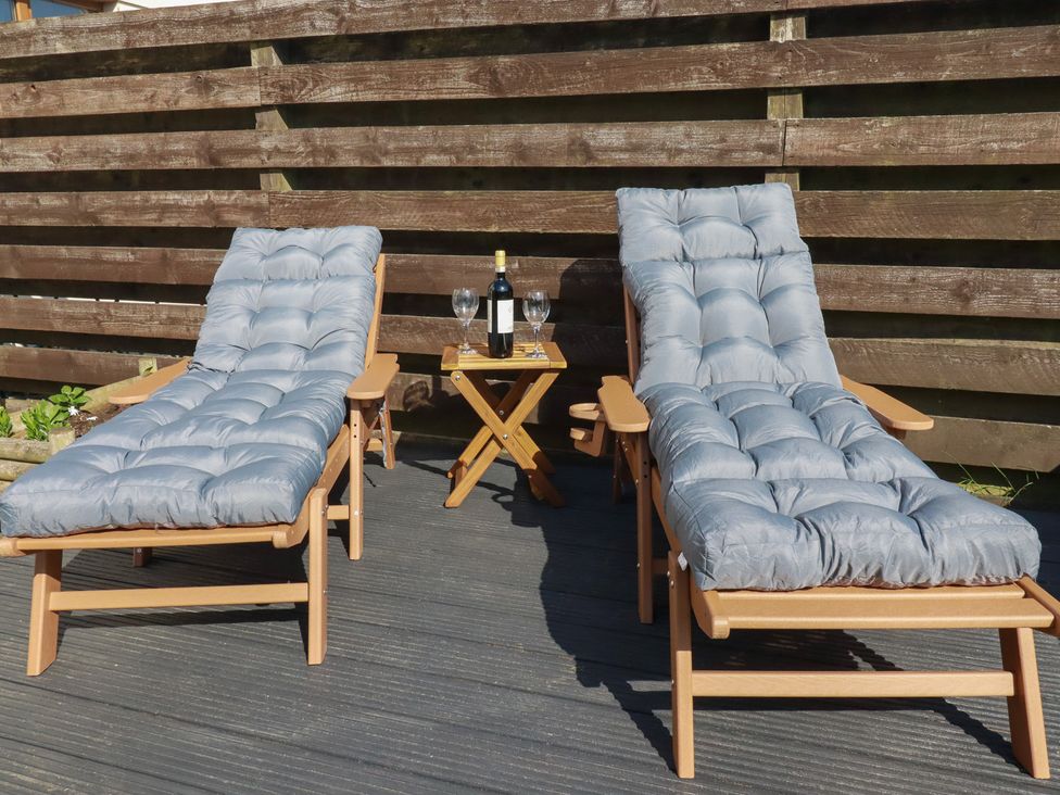 Two deck chairs and a small table with wine and glasses at Carnweather in Newquay