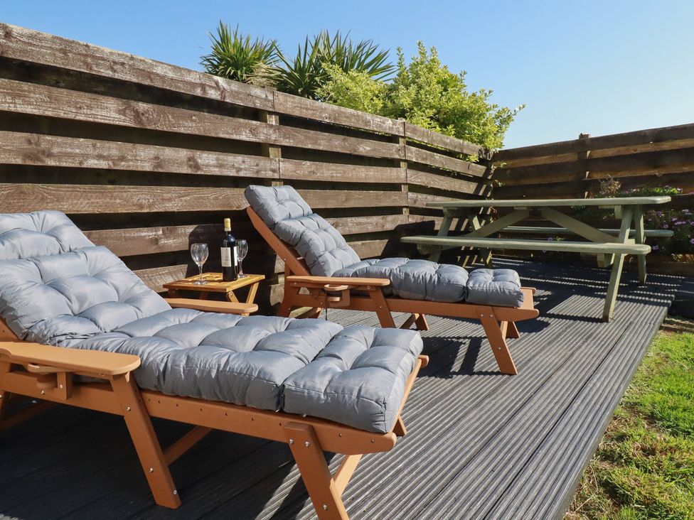 An outdoor seating area with deck chairs and a table at Carnweather in Newquay