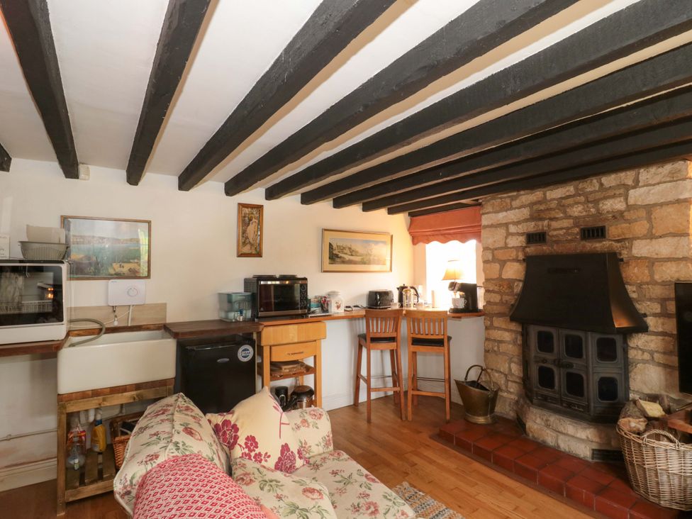 A living room with a fireplace and kitchen counter at The Annexe at Cherry Cottage Upton St Leonards