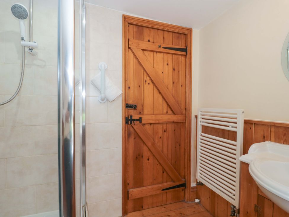 A bathroom with a shower and wooden door at The Annexe at Cherry Cottage Upton St Leonards