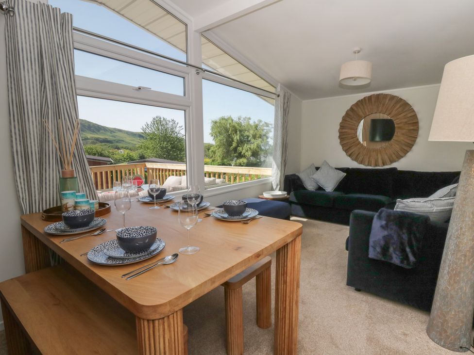 A dining area with a table set for meals and a sofa at Chalet 47 Erw Porthor Tywyn