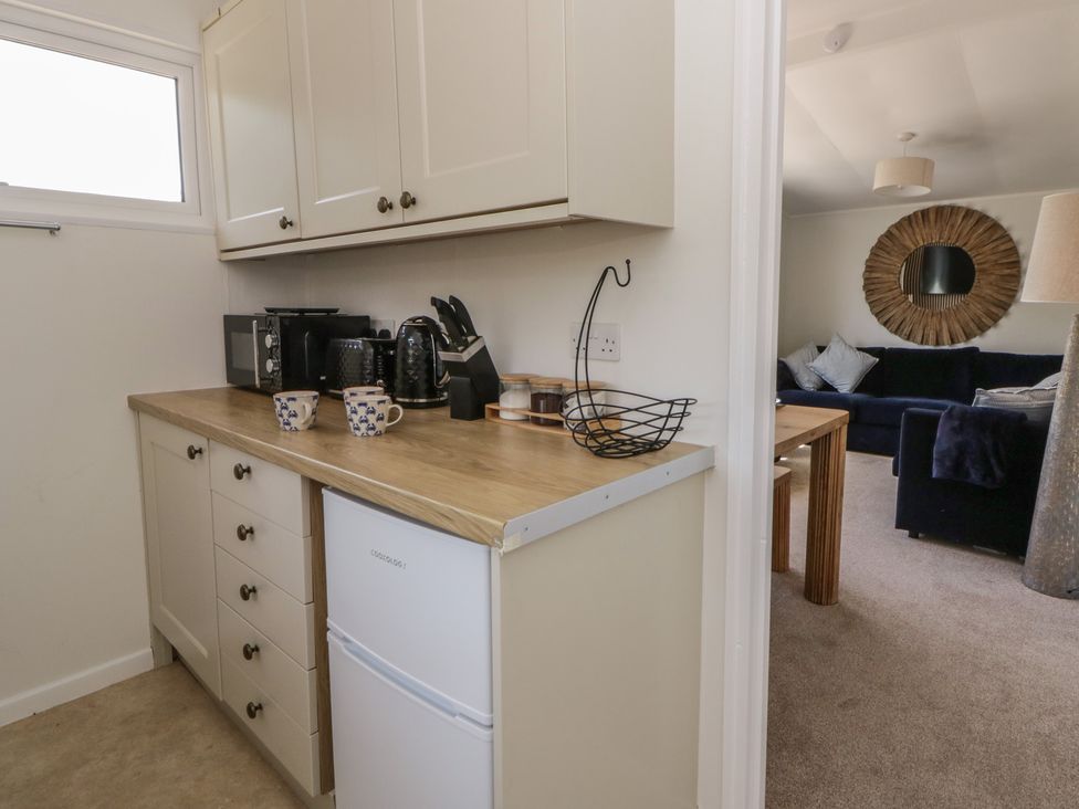 A kitchen with appliances and cabinets at Chalet 47 Erw Porthor Tywyn