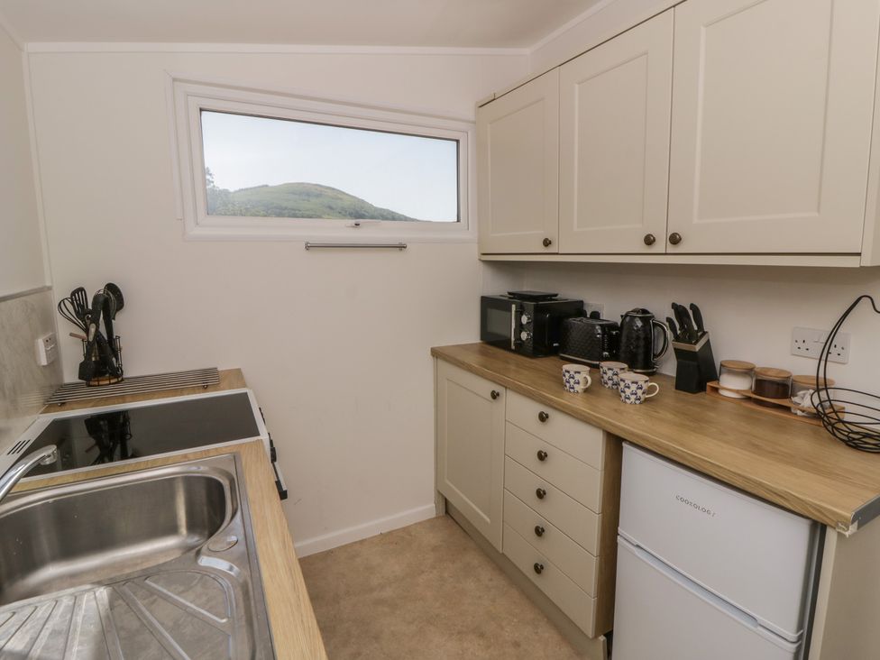A kitchen with a sink, stove and appliances at Chalet 47 Erw Porthor in Tywyn