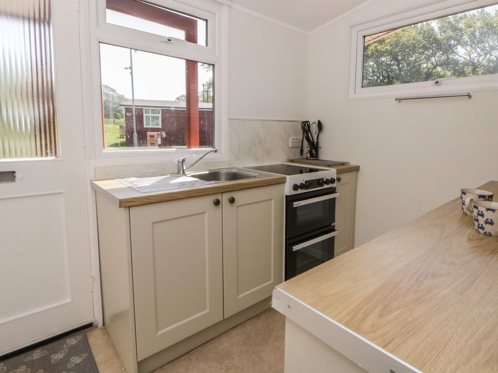 A kitchen with sink and oven at Chalet 47 Erw Porthor Tywyn