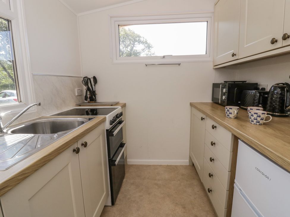 A kitchen with a sink and cooker at Chalet 47 Erw Porthor Tywyn