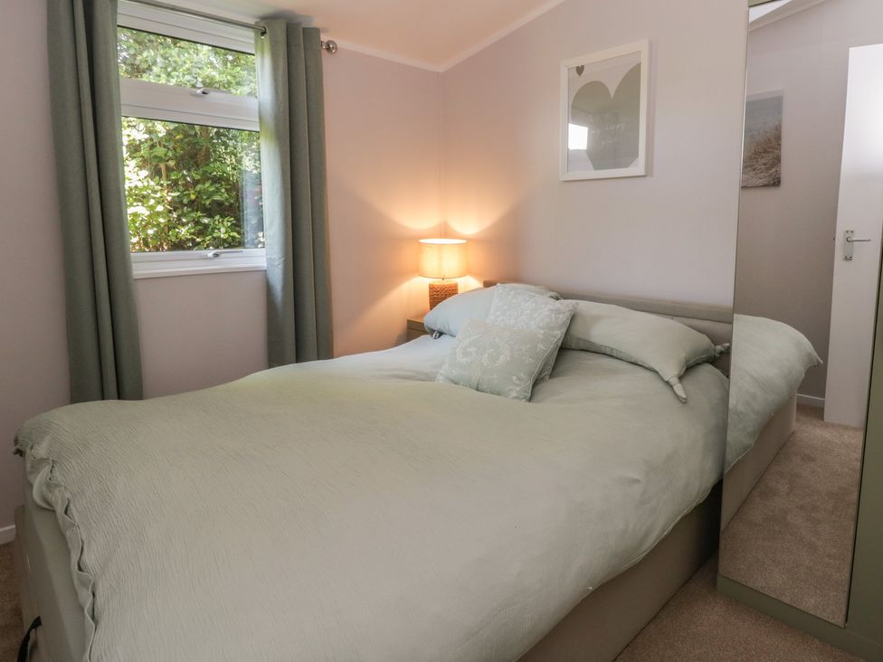 A bedroom with a bed and lamp at Chalet 47 Erw Porthor Tywyn