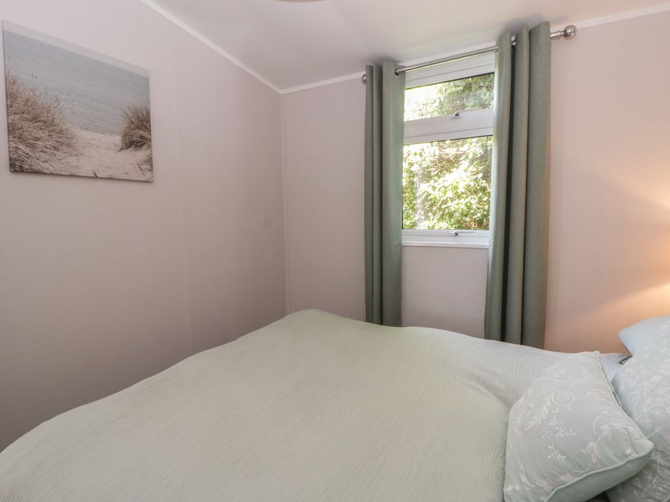 A bedroom with a bed and window at Chalet 47 Erw Porthor Tywyn