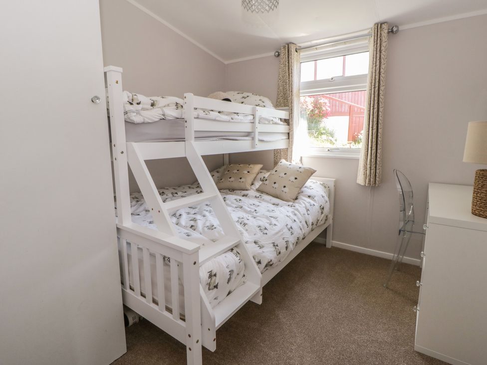 A bedroom with a bunk bed and a single bed at Chalet 47 Erw Porthor in Tywyn