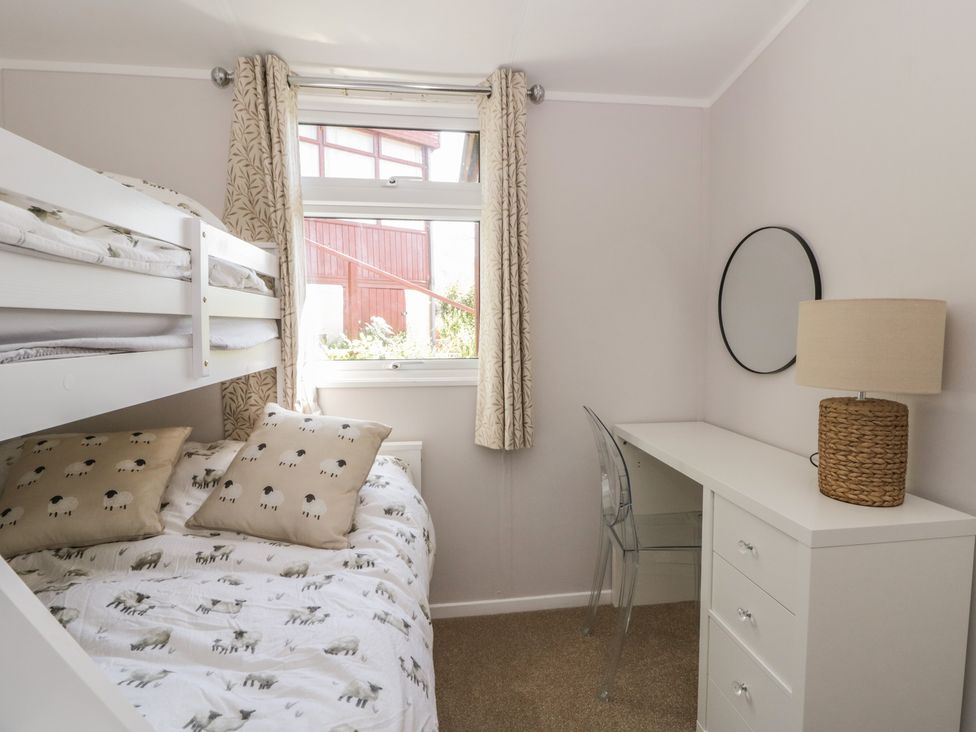 A bedroom with a bunk bed and a desk at Chalet 47 Erw Porthor, Tywyn