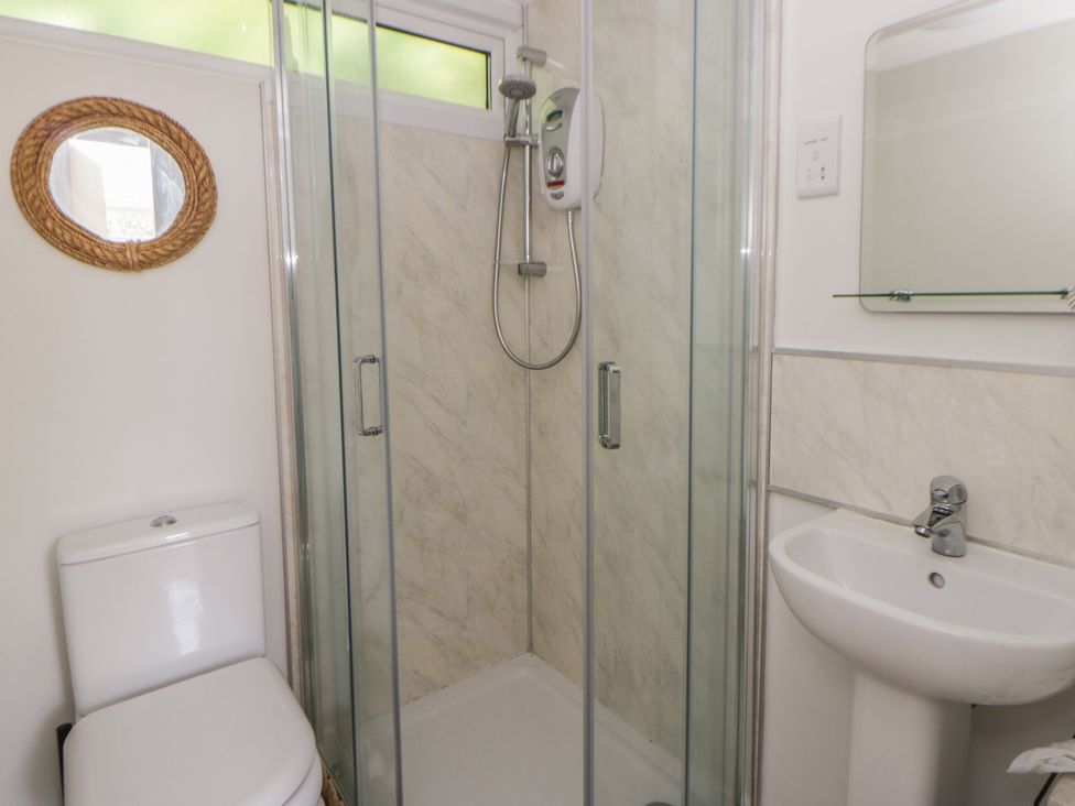 A bathroom featuring a shower, toilet, and sink at Chalet 47 Erw Porthor Tywyn