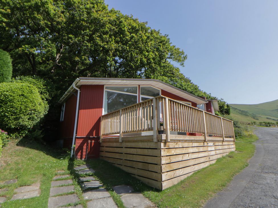 A cottage with wooden decking and pathway at Chalet 47 Erw Porthor Tywyn