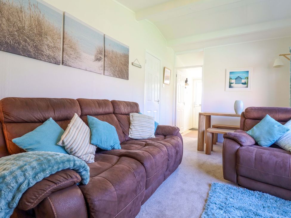 A living room with a sofa and table at Chalet 23 Erw Porthor in Tywyn
