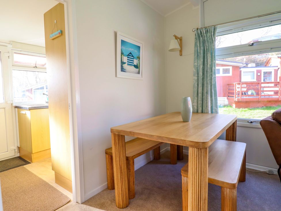 A dining area with a table and benches at Chalet 23 Erw Porthor Tywyn