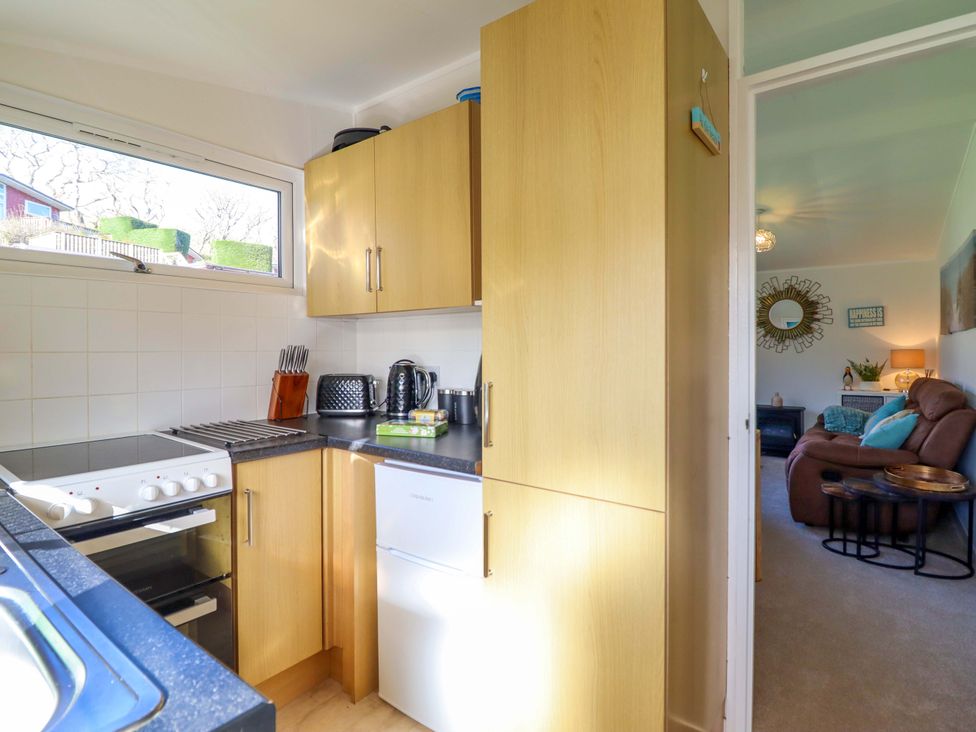 A kitchen with cabinets, oven, and sink at Chalet 23 Erw Porthor Tywyn