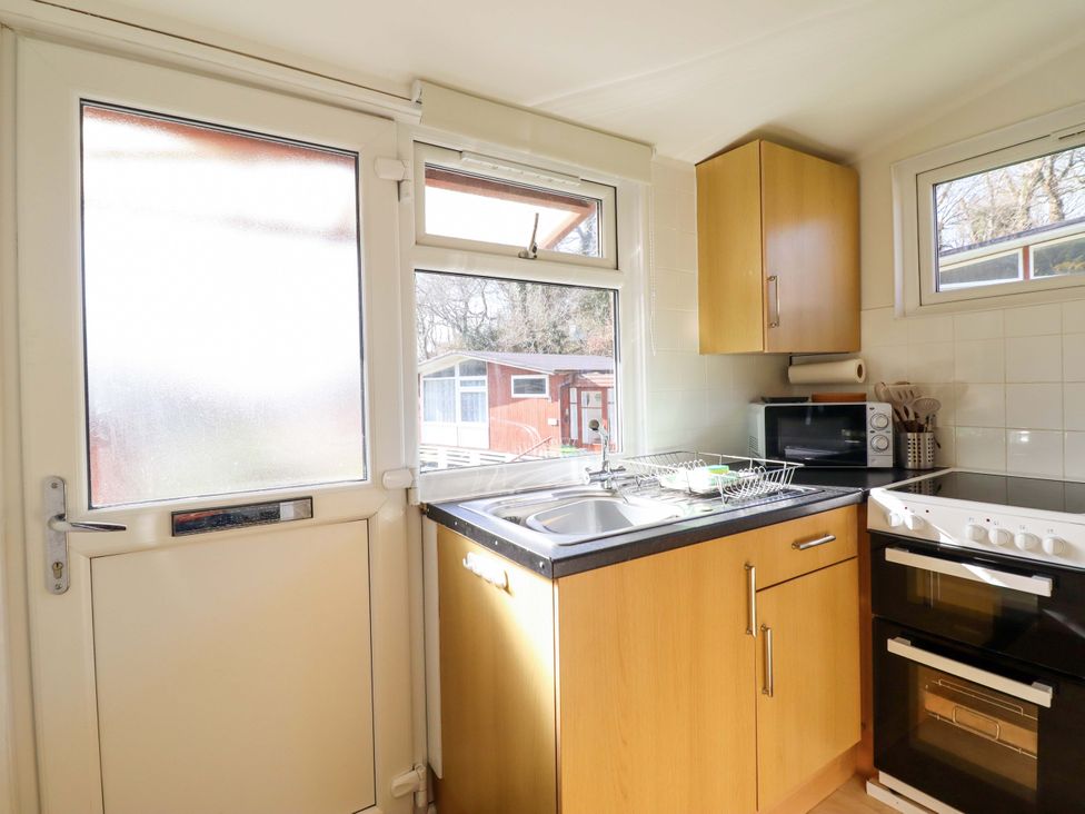 A kitchen with a sink, microwave and oven at Chalet 23 Erw Porthor Tywyn