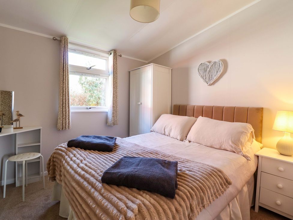 A bedroom with a bed and desk at Chalet 23 Erw Porthor Tywyn