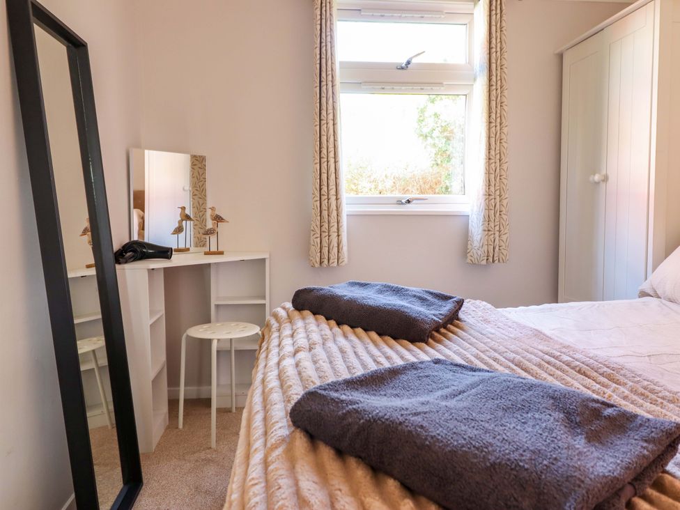 A bedroom with a bed and mirror at Chalet 23 Erw Porthor Tywyn