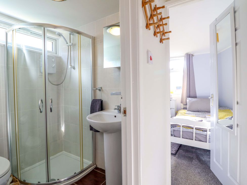 A bathroom with shower and sink adjacent to a bedroom at Chalet 23 Erw Porthor Tywyn