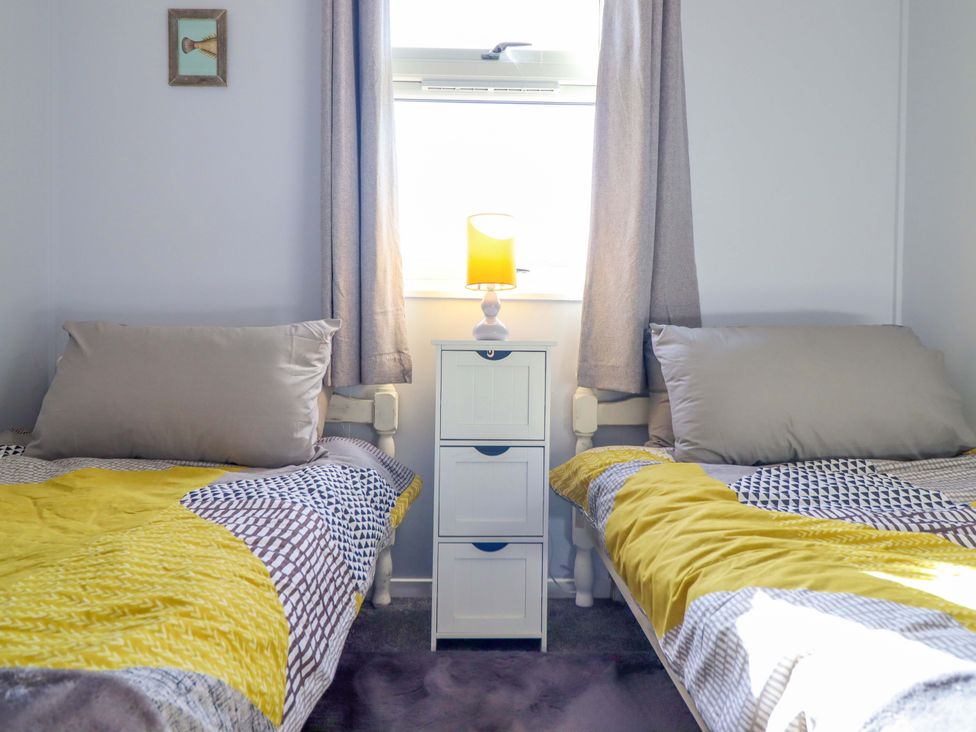A bedroom with two single beds and a nightstand at Chalet 23 Erw Porthor Tywyn